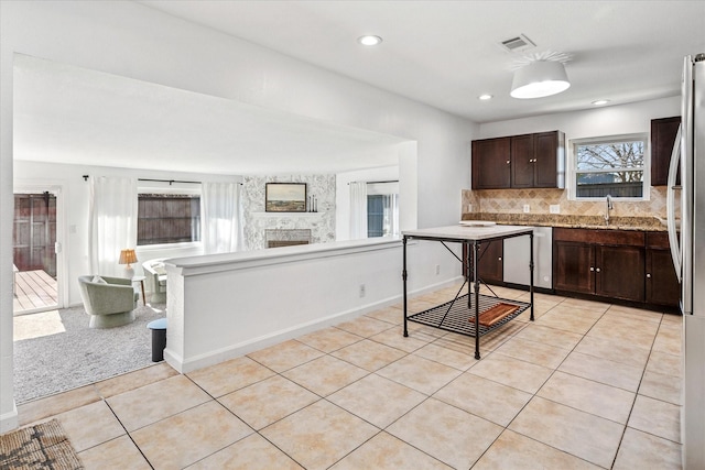 kitchen with light tile patterned floors, visible vents, dark brown cabinetry, stainless steel dishwasher, and tasteful backsplash