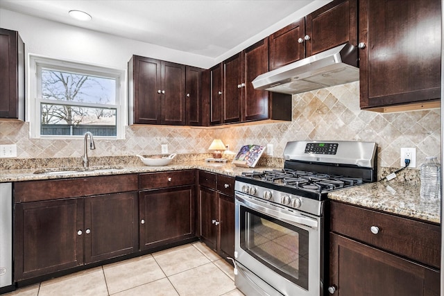 kitchen featuring under cabinet range hood, decorative backsplash, stainless steel gas range, and a sink