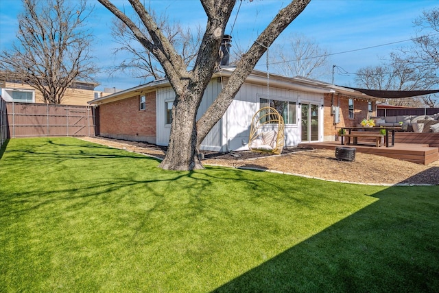 back of property with a yard, brick siding, and fence