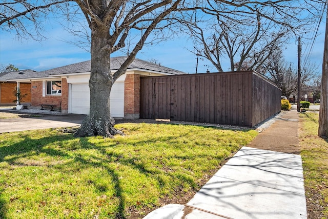 view of side of home with concrete driveway, an attached garage, brick siding, and a yard