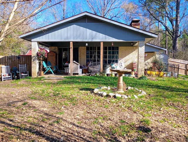 view of front of home with a front lawn, brick siding, a chimney, and fence