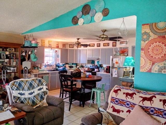 interior space with a sink, a textured ceiling, freestanding refrigerator, light tile patterned floors, and vaulted ceiling