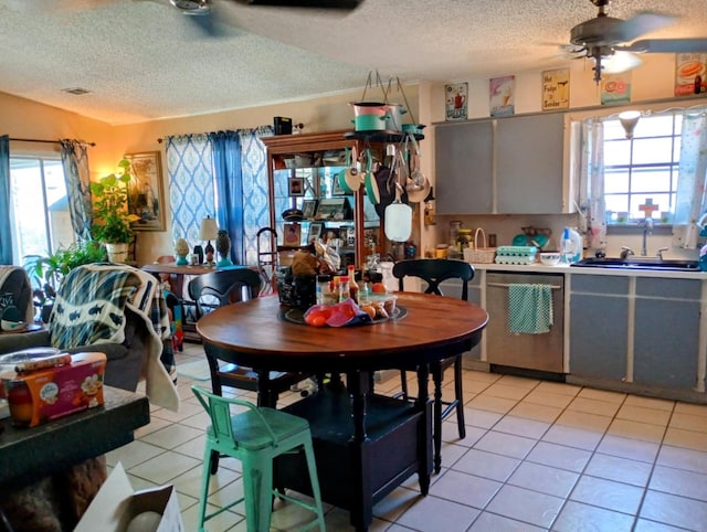 kitchen with stainless steel dishwasher, light tile patterned floors, plenty of natural light, and a sink