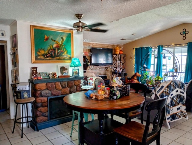 dining area with light tile patterned flooring, a textured ceiling, a large fireplace, and vaulted ceiling