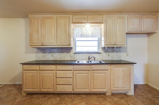 kitchen featuring dark countertops, light brown cabinets, tasteful backsplash, and a sink