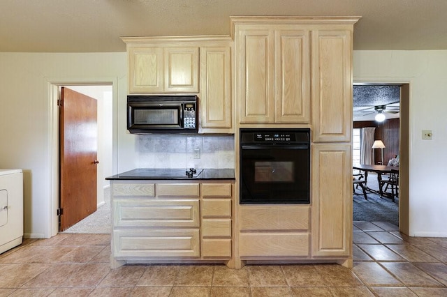 kitchen featuring black appliances, dark countertops, light brown cabinetry, and washer / dryer