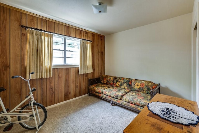 living area featuring baseboards, carpet floors, and wood walls