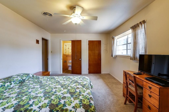 carpeted bedroom featuring ceiling fan, visible vents, baseboards, and connected bathroom