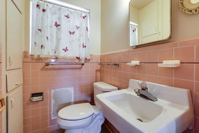 bathroom featuring a sink, a wainscoted wall, and toilet