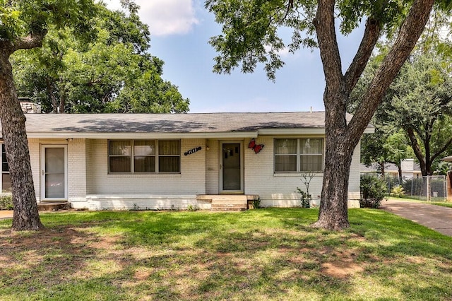 ranch-style home with brick siding, a chimney, a front lawn, and fence