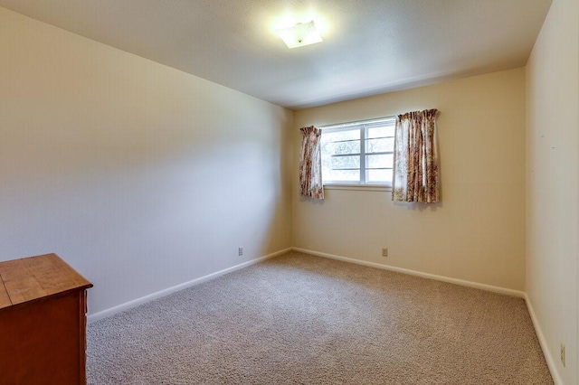 spare room with baseboards and carpet floors