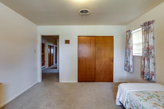 carpeted bedroom with a closet, visible vents, and baseboards