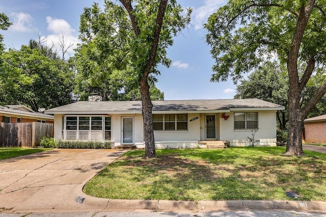 ranch-style house featuring a front lawn, fence, brick siding, and a chimney