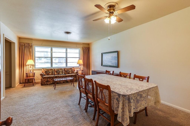 carpeted dining area with baseboards, visible vents, and ceiling fan