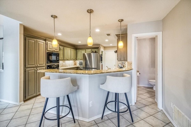 kitchen featuring visible vents, freestanding refrigerator, black microwave, a kitchen breakfast bar, and tasteful backsplash