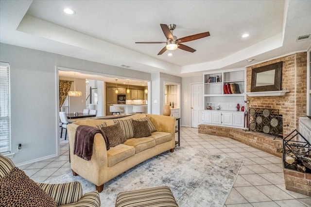 living room featuring built in features, a tray ceiling, visible vents, and light tile patterned flooring