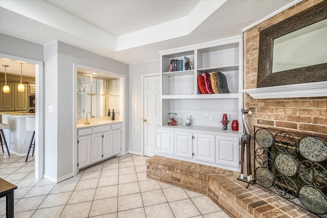 interior space featuring a sink, built in features, a brick fireplace, and light tile patterned floors