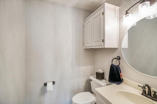 half bath featuring crown molding, vanity, and toilet