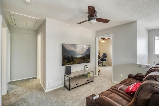 carpeted living area featuring visible vents, a ceiling fan, a textured ceiling, baseboards, and attic access