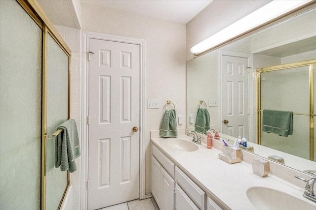 bathroom with tile patterned flooring, a shower with shower door, double vanity, and a sink