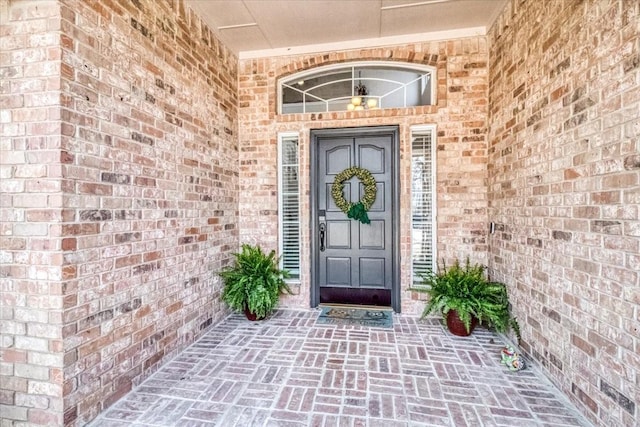 view of exterior entry featuring brick siding