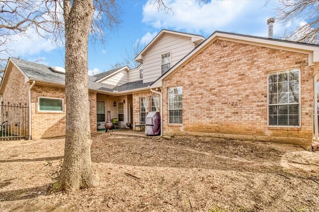 back of house with a patio area, brick siding, and a shingled roof