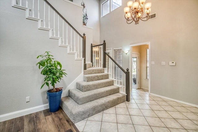 foyer with visible vents, baseboards, stairs, a towering ceiling, and a chandelier