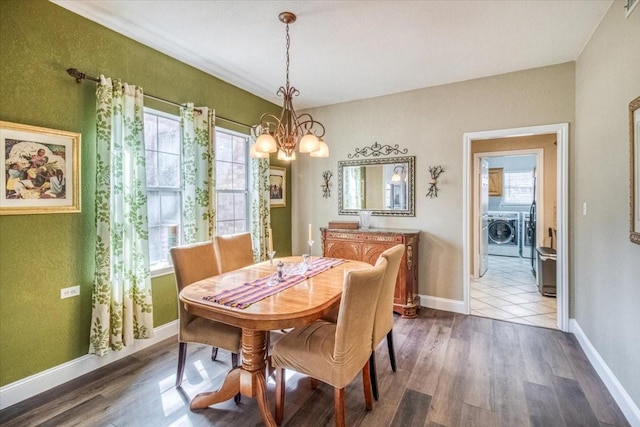 dining area featuring an inviting chandelier, washer / dryer, wood finished floors, and a healthy amount of sunlight