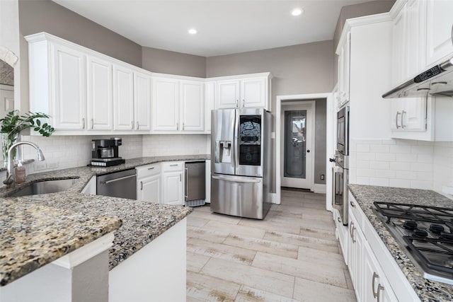 kitchen featuring appliances with stainless steel finishes, white cabinetry, extractor fan, and a sink