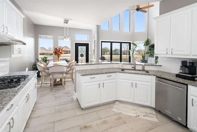 kitchen featuring tasteful backsplash, white cabinetry, a peninsula, and stainless steel appliances