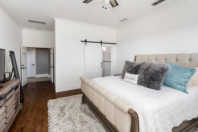 bedroom featuring a barn door, wood finished floors, and visible vents