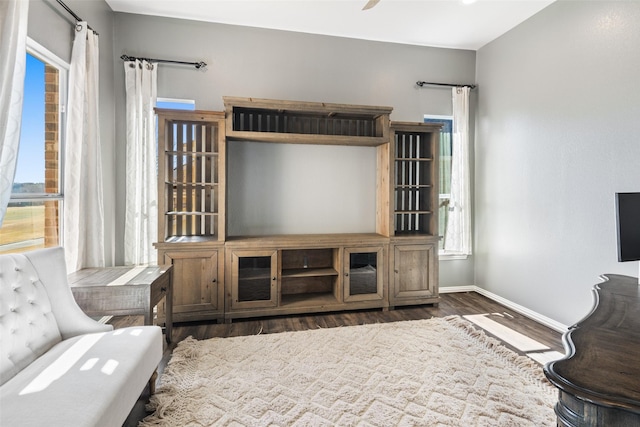 living area with baseboards, wood finished floors, and a ceiling fan