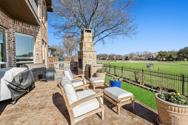 view of patio / terrace featuring area for grilling, an outdoor stone fireplace, and a fenced backyard