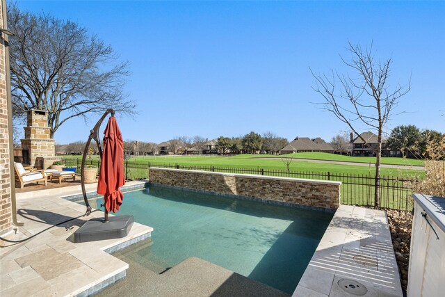 view of pool featuring a yard, a patio area, a fenced backyard, and an outdoor fireplace