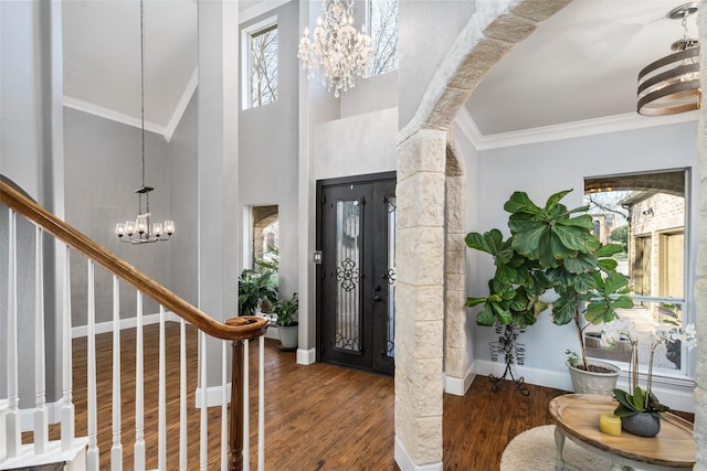 foyer entrance with crown molding, baseboards, stairway, wood finished floors, and a notable chandelier