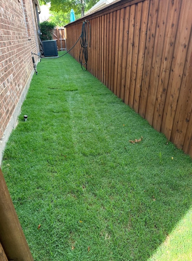 view of yard with central AC unit and fence