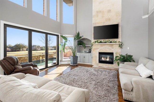 living room featuring dark wood-type flooring, a high ceiling, and a fireplace