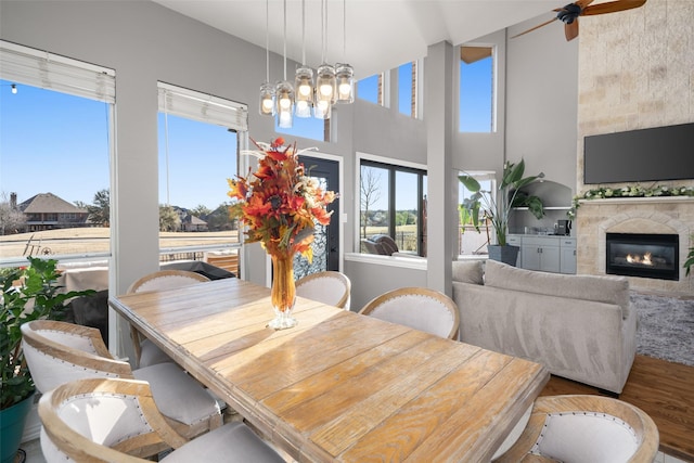 dining area with wood finished floors, a notable chandelier, a glass covered fireplace, and a towering ceiling