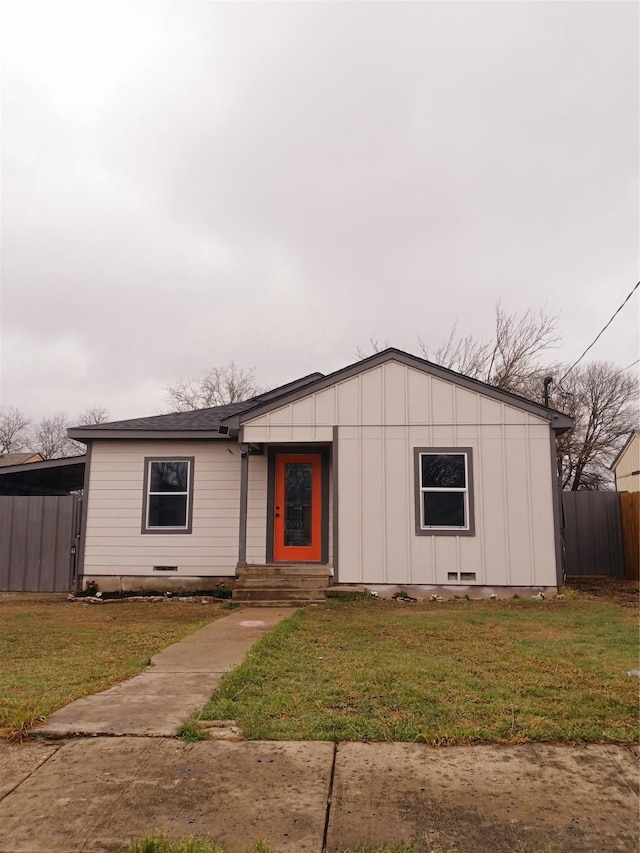 view of front facade featuring a front lawn, fence, board and batten siding, and crawl space