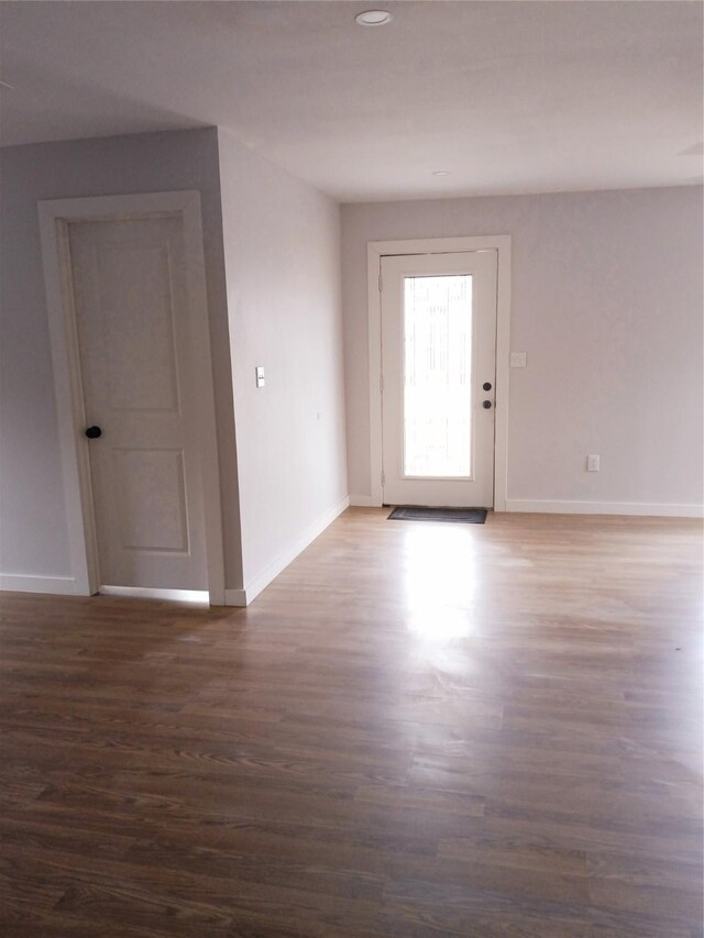 interior space with a glass covered fireplace, ceiling fan, baseboards, and wood finished floors