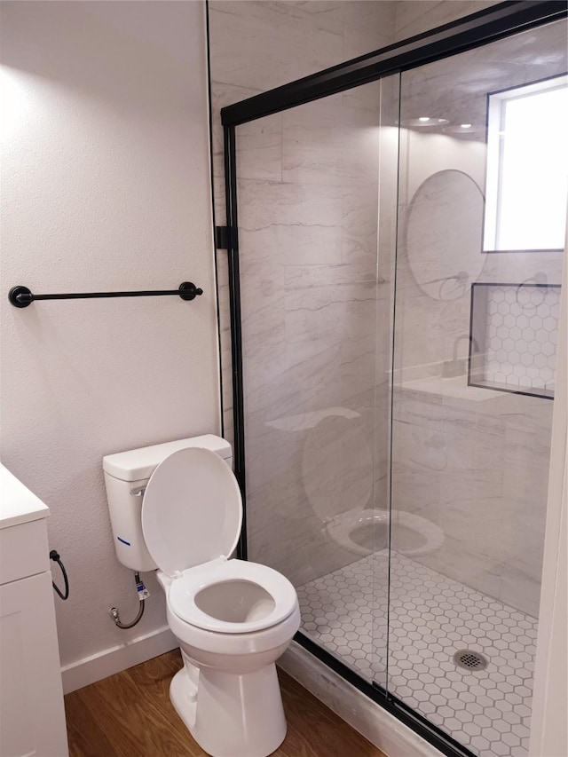 full bath featuring toilet, wood finished floors, a stall shower, and baseboards