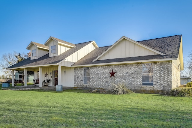 exterior space with a porch, a yard, brick siding, and roof with shingles