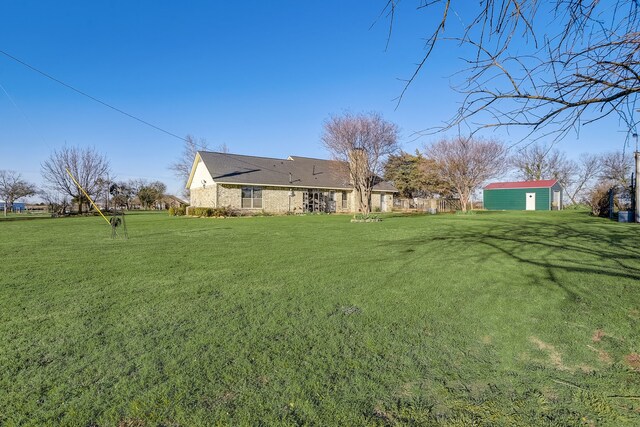 view of yard featuring an outbuilding, a storage unit, and fence