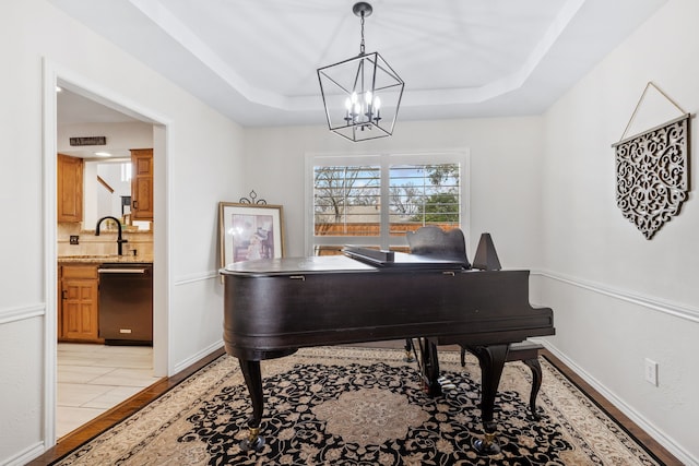 living area with a tray ceiling, baseboards, and a notable chandelier