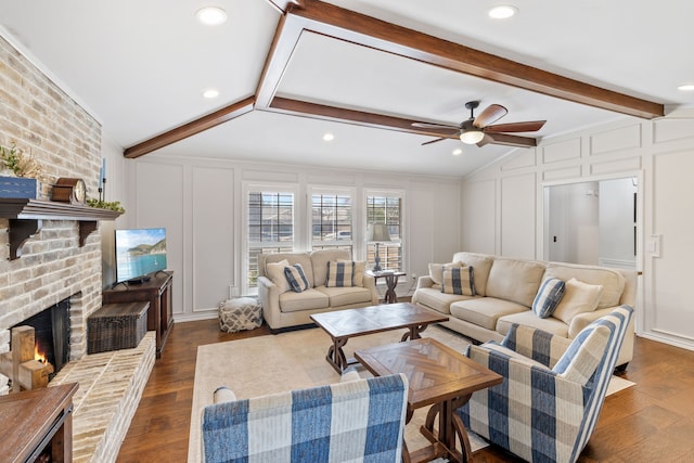 living area featuring dark wood finished floors, a decorative wall, vaulted ceiling with beams, and a fireplace