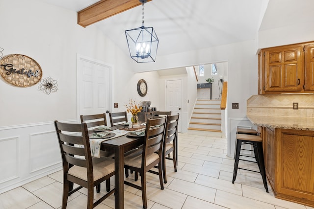 dining room featuring a wainscoted wall, stairway, a decorative wall, a chandelier, and vaulted ceiling with beams