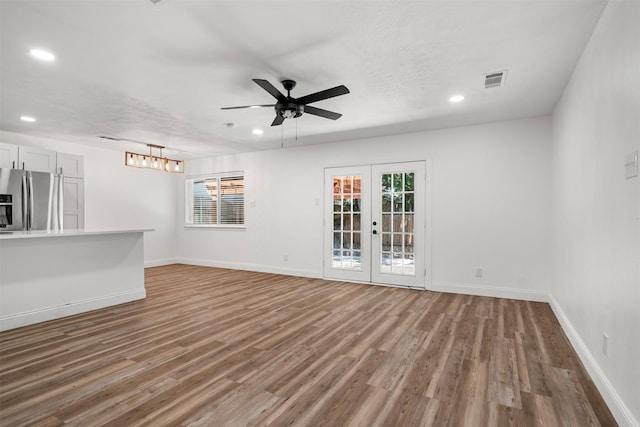 unfurnished living room featuring wood finished floors, baseboards, and french doors