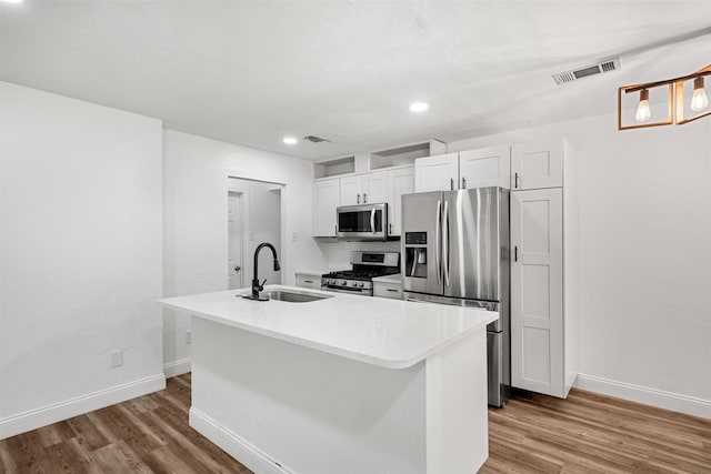 kitchen with a sink, stainless steel appliances, visible vents, and wood finished floors