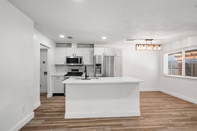 kitchen featuring wood finished floors, visible vents, a sink, stainless steel appliances, and light countertops