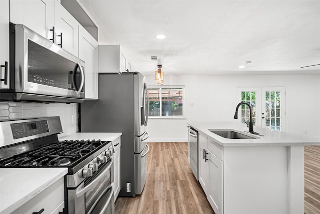 kitchen with visible vents, light wood-style flooring, a sink, stainless steel appliances, and decorative backsplash